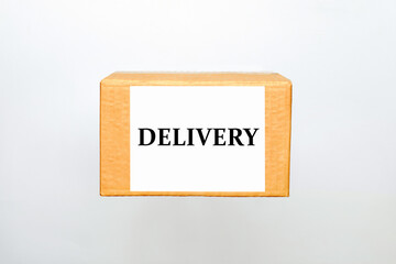 Cardboard box with a label and the inscription delivery on a white background with copy space. The concept of gifts in a box and online home delivery