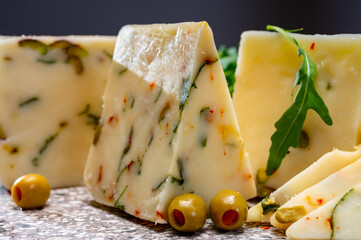 Cheese collection, fresh Italian pecorino cheese made from sheep milk filled with green olives stuffed with red paprika, green ruccola rocket salad and cayenne pepper