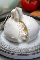Eating of fresh handmade soft Italian cheese from Puglia, white balls of burrata or burratina cheese made from mozzarella and cream filling