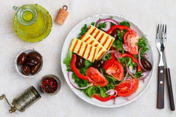 Delicious salad with grilled halloumi cheese, lettuce, tomatoes, bell peppers, red onions, Kalamata olives, olive oil, spices. Mediterranean cuisine. Selective focus