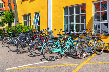 Fototapeta na wymiar Many bicycles parked in front of a yellow house. Copenhagen. Denmark. Bicycles are one of the main means of transportation ..