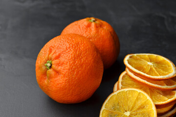 Fresh mandarins and dry orange slices on dark background
