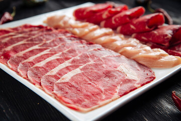 Sliced meat assorti on the white square plate