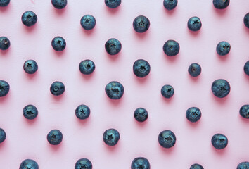 Fresh blueberries are laid out in a pattern on a lilac background with soft light and shadows, a bright poster.