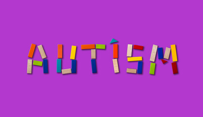 Concept of autism. Wooden word on colored background