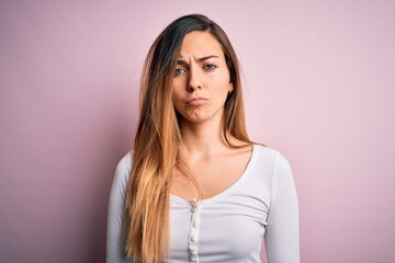 Fototapeta premium Young beautiful blonde woman with blue eyes wearing white t-shirt over pink background depressed and worry for distress, crying angry and afraid. Sad expression.