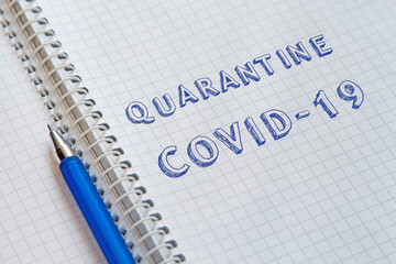 Lettering Quarantine COVID-19 on sheet of notebook