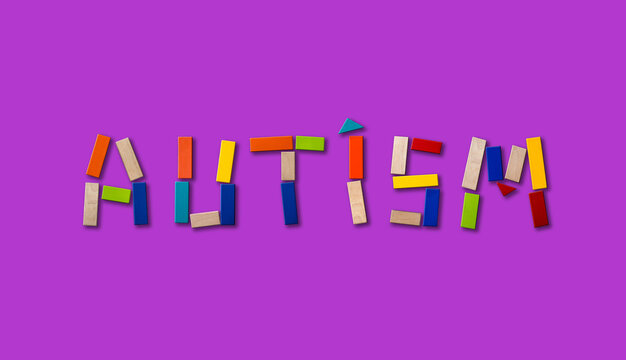 Concept of autism. Wooden word on colored background
