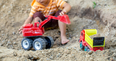 Fototapeta na wymiar The boy is playing his toy on the pile of soil. At his home to be safe from an epidemic