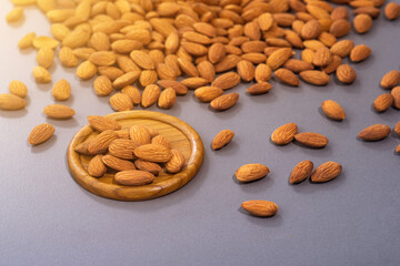 Raw peeled almonds freely laid with sunlight on gray stone table background.