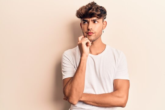 Young hispanic man wearing casual clothes thinking concentrated about doubt with finger on chin and looking up wondering
