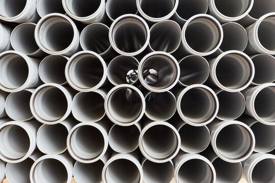 Gray plastic pipes lie in rows