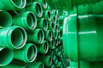 Green plastic pipes lie in rows