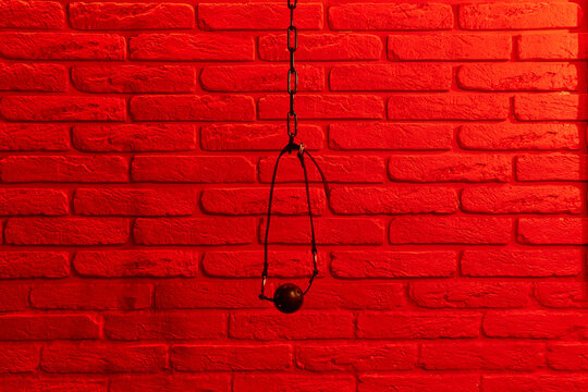Black ball gag in mouth on red brick wall