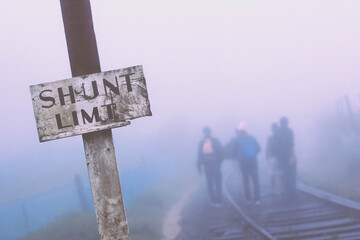 Rail hikers accelerate their foots on the rails beyond the shunt limit in a foggy setting.