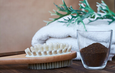 Brush, washcloth for body massage and skin cleaning with natural coffee scrub on beige background. Spa.