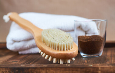 Brush, washcloth for body massage and skin cleaning with natural coffee scrub on beige background. Spa.