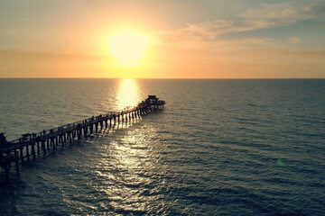 Fototapeta premium Sunset over the Gulf of Mexico, flying above pier.