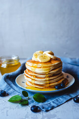 A stack of pancakes with fresh banana, blueberry and honey. Delicious homemade breakfast.