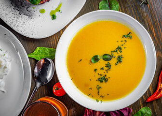 Pumpkin soup in white plate on wooden table background