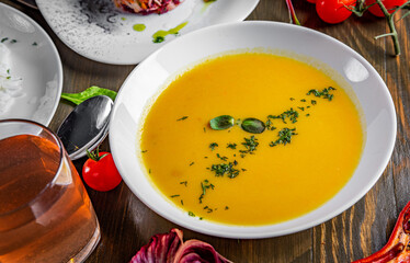 Pumpkin soup in white plate on wooden table background