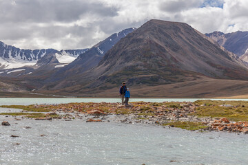 Fototapeta premium Father and son are walking along the grass near the mountain lake of the Mongolian Altai