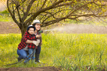 woman gardener with son watering garden