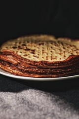 Thin crepes, pancakes or blinis on slate isolated on black background, tasty breakfest