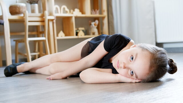 Little girl ballerina tired of dancing and learning new movements and lay on the floor.