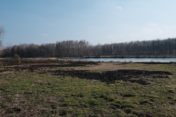 Last year burning grass on the bank of a small river in the red rays of the evening sun