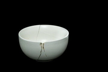 Pieces of broken white ceramic bowl on black background. Copyspace, place for text. Break, fragment.