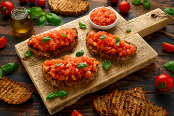 Tomato bruschetta seasoned with basil on a rustic wooden board