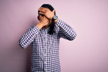 Young handsome african american afro man with dreadlocks wearing casual shirt Covering eyes and mouth with hands, surprised and shocked. Hiding emotion