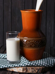 Homemade milk in a jug and in a clear glass on an old wooden background. Rustic. Milk products. Background image, copy space