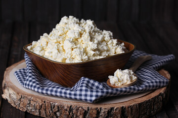 Homemade cottage cheese, curd in a wooden bowl on an old wooden background with a spoon. Rustic. Milk products. Background image, copy space