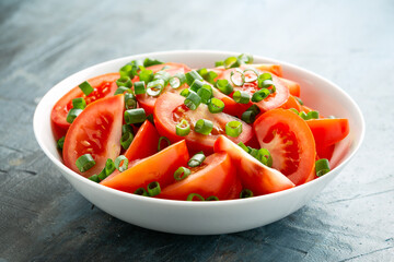 Tomato salad with spring onion and herbs in white bowl. Healthy summer food