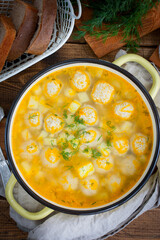 Potato soup with meatballs in an enameled pan on a wooden table, selective focus