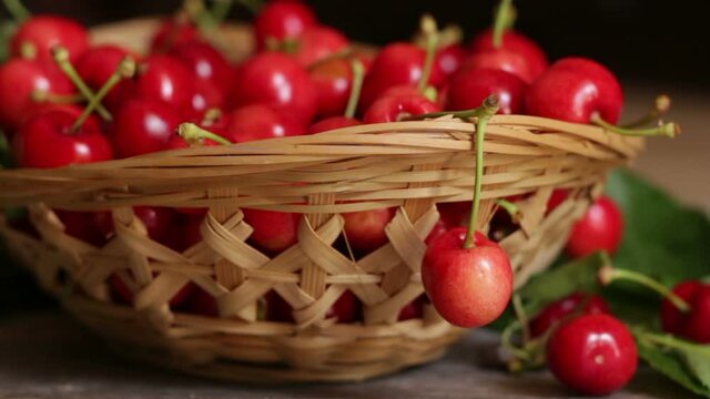 Basket of sweet and ripe cherries with leaves on wooden background
