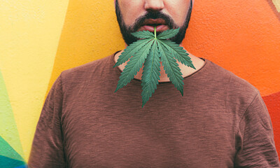 Young bearded man with a marijuana leaf in his mouth - Cannabis medicine, healthy lifestyle and...