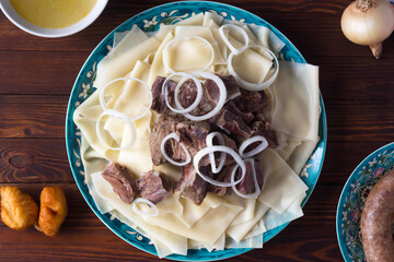 National Kazakh dish - Beshbarmak and bouillon in the bowls, view from above
