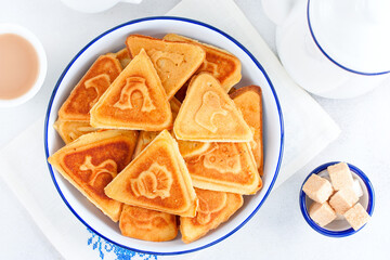 Traditional Russian cookies, cooked on a plate in the form with prints, without baking in an enameled white bowl, selective focus