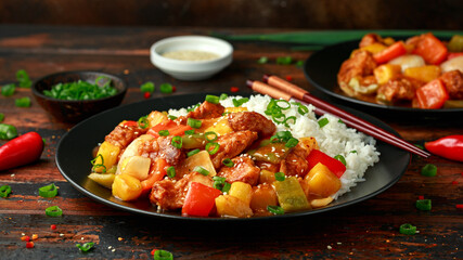 Pineapple and Chicken in sweet and sour sauce with bell pepper, rice and spring onion on wooden table