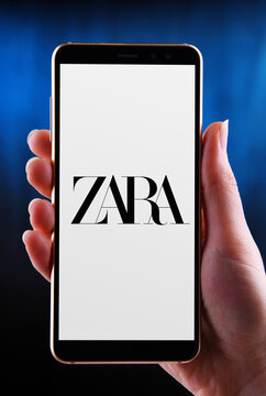Hands holding smartphone displaying logo of Zara