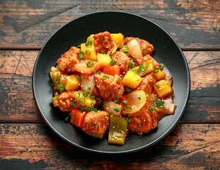 Pineapple and Chicken in sweet and sour sauce with bell pepper in black plate