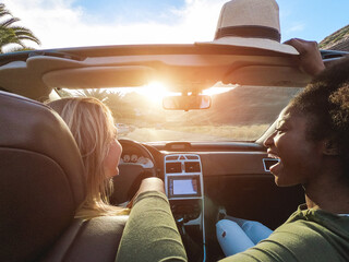 Happy girls having fun in convertible car in summer vacation - Young women friends laughing on...