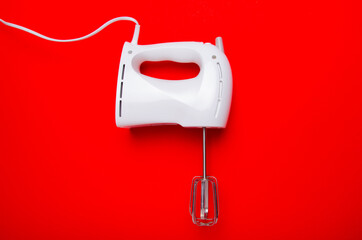 Hand electric blender mixer on red background. Flat lay, Top view, copy space.