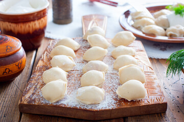 Raw homemade dumplings on a wooden board, selective focus