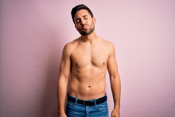 Fototapeta premium Young handsome strong man with beard shirtless standing over isolated pink background looking at the camera blowing a kiss on air being lovely and sexy. Love expression.