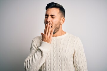 Fototapeta na wymiar Young handsome man wearing casual sweater standing over isolated white background bored yawning tired covering mouth with hand. Restless and sleepiness.