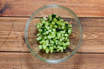 Step-by-step preparation of salad with salted salmon, fresh cucumbers and herbs, step 2 - chopped fresh cucumber, top view, selective focus